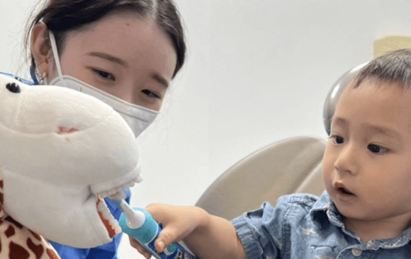 Dentist attending to toddler with a toy